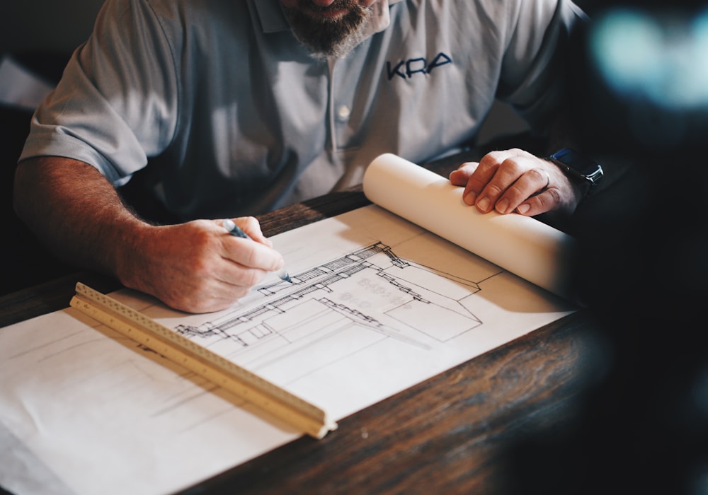 An architect drawing a building section by hand with a scale ruler