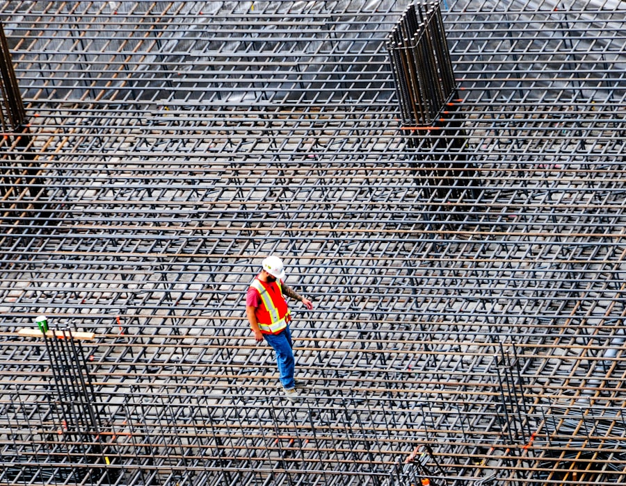 A construction worker walking across a grid of rebar on a building site